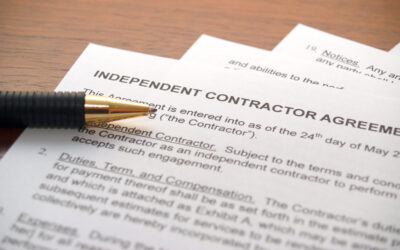 A pen rests on top of an independent contractor agreement, dated May 24th, 20--. The document outlines terms for engaging independent contractors and includes sections on duties, payment, and terms.